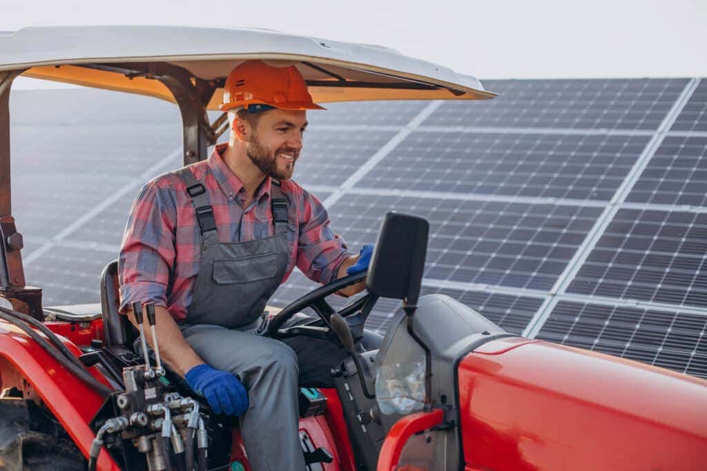 Mężczyzna jadący traktorem na tle paneli fotowoltaicznych